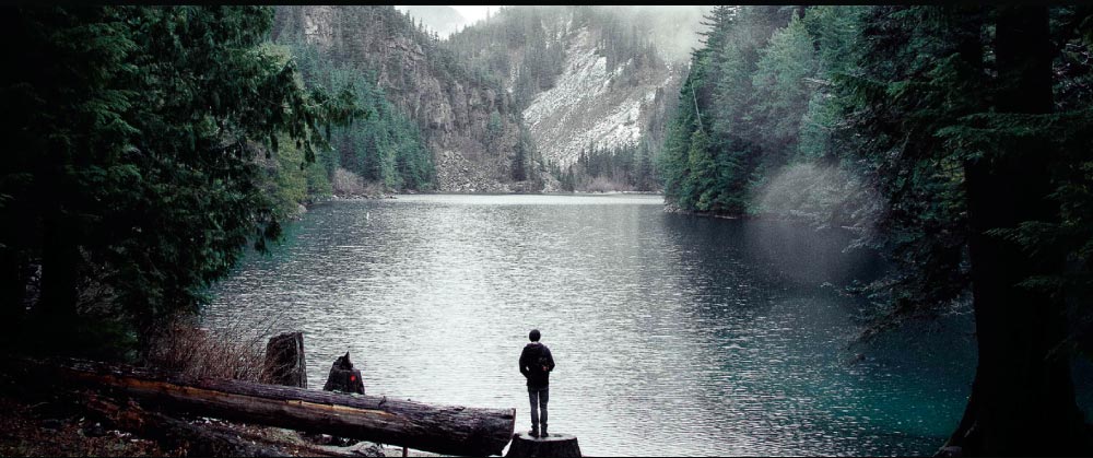 Person-standing-at-lake-edge-in-mountains-50
